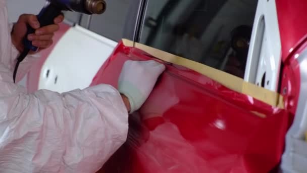 Применение красной виниловой упаковки автомобиля с помощью теплового пистолета — стоковое видео