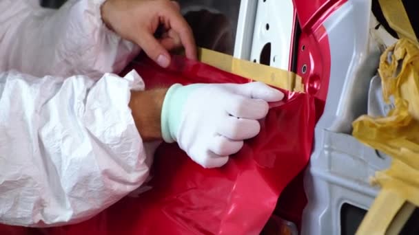 Працівник склеює стрічку на кузові автомобіля під час ремонтних робіт — стокове відео