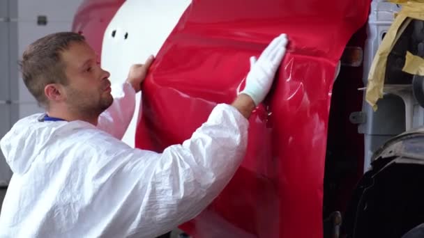 Работник закрывает двери автомобиля лентой, во время ремонтных работ — стоковое видео