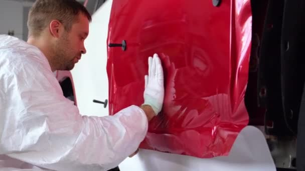 Рабочий устанавливает виниловую ленту на кузов автомобиля — стоковое видео