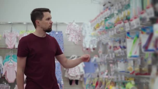 Ο άνθρωπος επιλέγει αξεσουάρ μωρού στο κατάστημα — Αρχείο Βίντεο