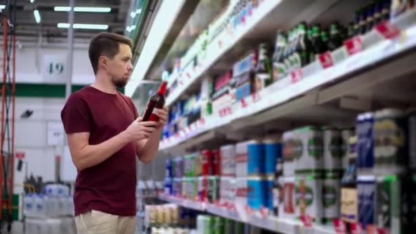 Чоловік купує пляшкове пиво в супермаркеті — стокове відео