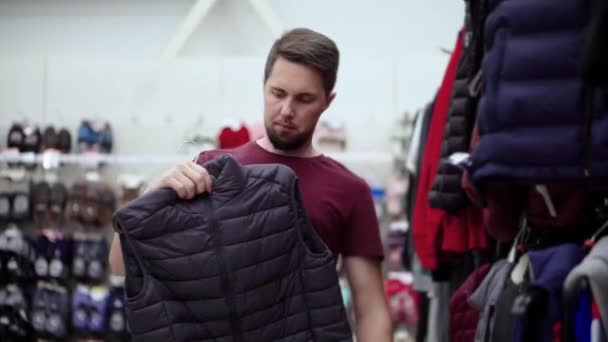 Man buying down sweater vest in clothing store — Stock Video