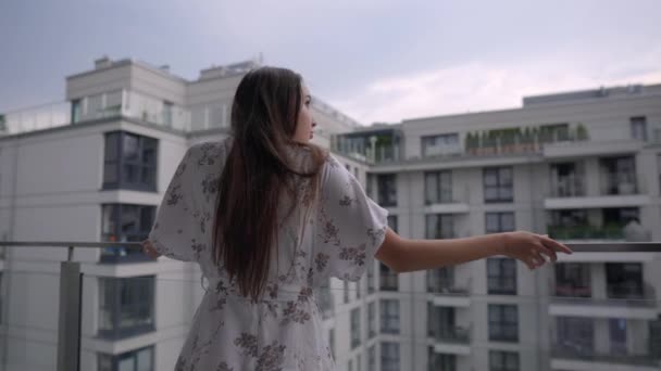 Frau blickt vom Balkon ihrer Wohnung auf die Stadt — Stockvideo