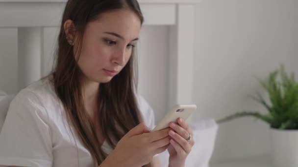 Chica usando el teléfono celular justo después de despertar — Vídeos de Stock