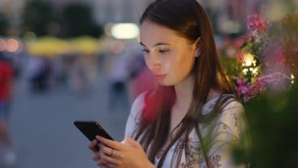 La fille qui attend le rendez-vous. Elle est seule avec mobile dans la ville du soir — Video