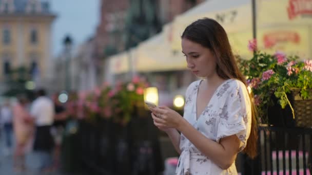 Mädchen mit Smartphone abends draußen — Stockvideo