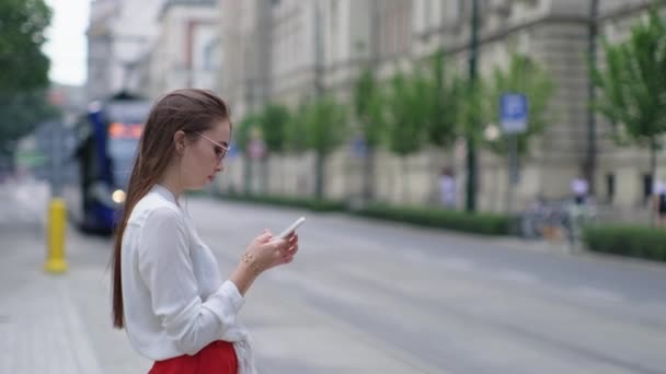 Menina esperando por bonde e usando smartphone em Cracóvia, Polônia — Vídeo de Stock