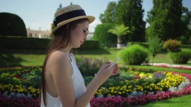 Çek Cumhuriyeti 'nin Lednice Sarayı parkında cep telefonu kullanan bir turist kız.