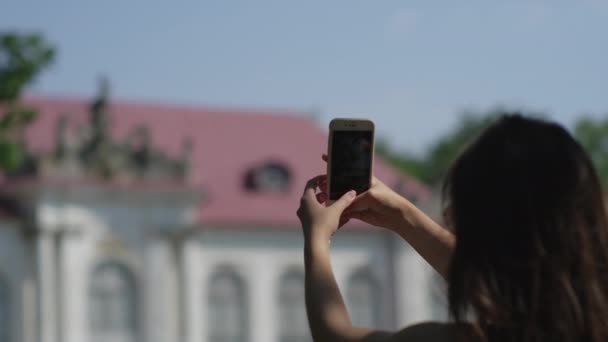 Женщина-путешественница фотографирует здание на смартфон — стоковое видео