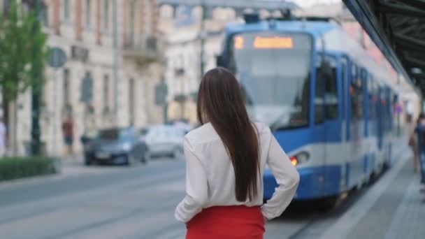 Habitante de la ciudad femenina está caminando en la estación de tranvía en la ciudad — Vídeo de stock
