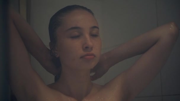 Молодая женщина моет голову в душе — стоковое видео