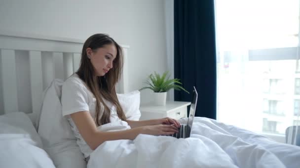 Kobieta pracuje z laptopem w sypialni, kłamie i pisze — Wideo stockowe