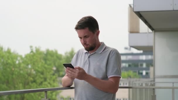 Mann mit Smartphone auf Wohnungsbalkon — Stockvideo