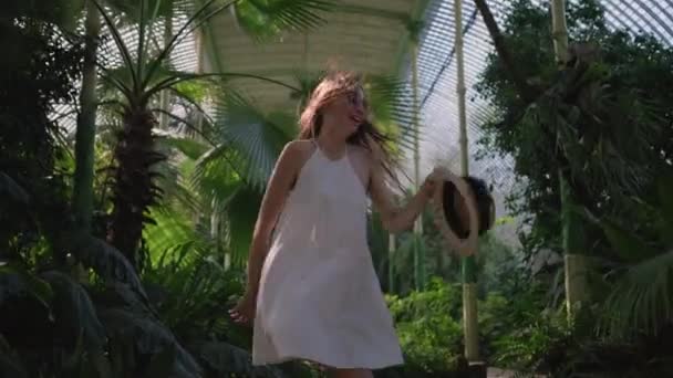 Молодая женщина бежит по дорожке большой теплицы — стоковое видео