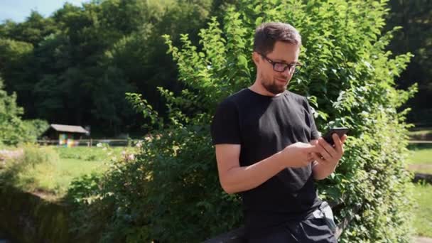 Άνθρωπος χρησιμοποιεί smartphone σε εξωτερικούς χώρους στον κήπο — Αρχείο Βίντεο