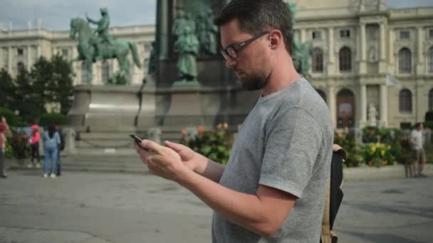 Homem está usando smartphone em pé na praça em Viena — Vídeo de Stock