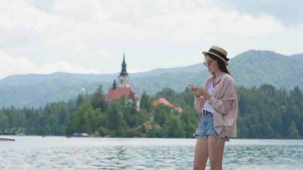 Meisje met mobiel in de buurt van Lake Bled in Slovenië — Stockvideo