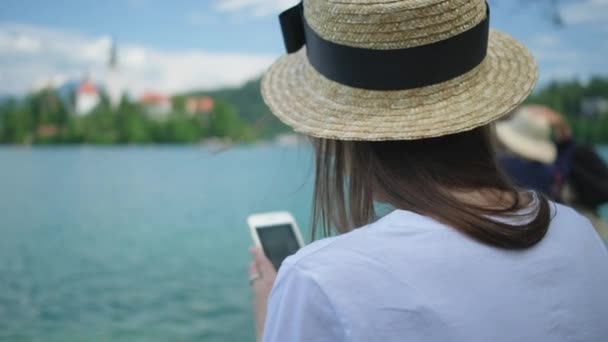 Turistka s mobilním telefonem na exkurzi po jezeře Bled ve Slovinsku — Stock video