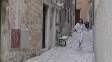 Kasaba caddesinde zıplayan ve dans eden neşeli kız. Rovinj, Hırvatistan