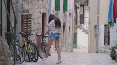 Genç kız eski Avrupa kasabasında şeritte zıplıyor