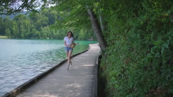 Mujer está corriendo y girando en la costa del lago en la naturaleza — Vídeos de Stock