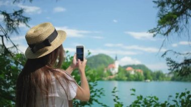 Kız Slovenya 'daki Bled Gölü manzarasını paylaşmak ve fotoğraf çekmek istiyor.