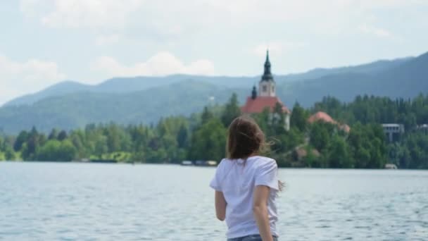 Mädchen besucht See und sieht Kirche auf slowenischer Insel — Stockvideo