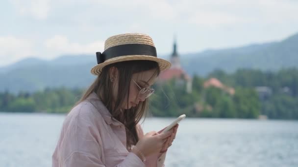 Flicka chatta på mobil nära Lake Bled, Slovenien — Stockvideo