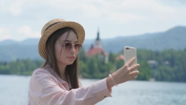 Viaggiatore donna sta prendendo selfie da smartphone sul lago di Bled in estate — Video Stock