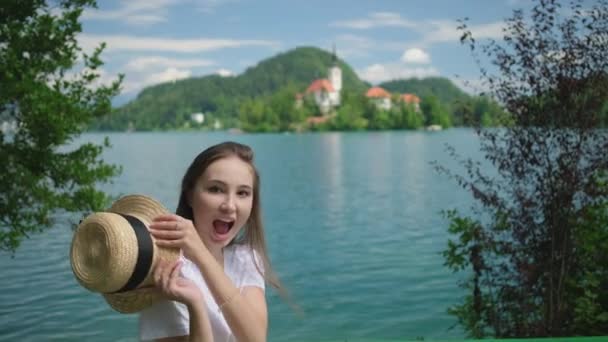 Tourist woman is posing on coast of Bled lake — стокове відео