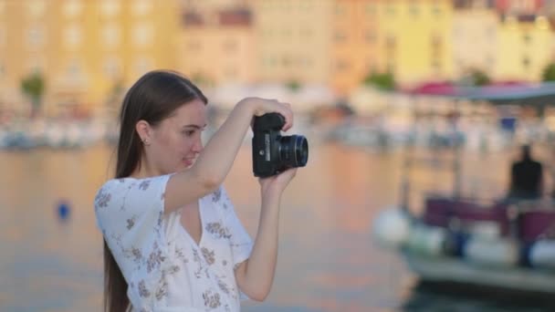 Vrouwelijke fotograaf maakt foto van stad in de buurt van zee — Stockvideo