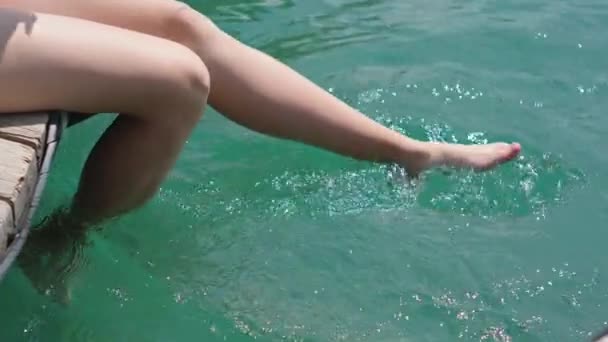 Meisje bungelende voeten in helder water van meer — Stockvideo