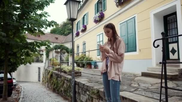 Egy lány okostelefonnal a város utcájában. Wachau völgy, Ausztria — Stock videók