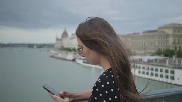Townswoman πληκτρολογεί μήνυμα στο κινητό τηλέφωνο στη γέφυρα Szechenyi στη Βουδαπέστη — Αρχείο Βίντεο