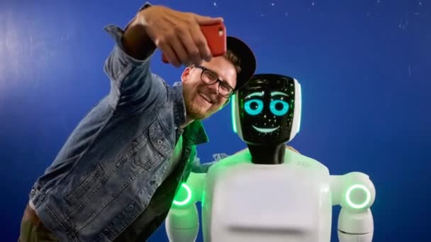 Adam sergilenen insansı robotla akıllı telefondan selfie çekiyor. — Stok video