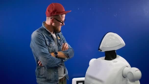 Человек смотрит на улыбающегося робота-гуманоида на выставке — стоковое видео