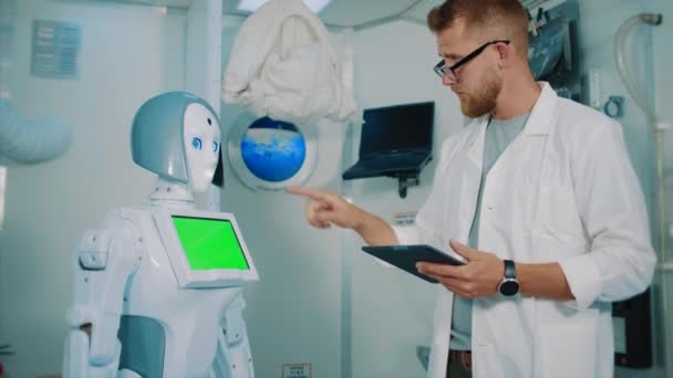 Человек-инженер программирует робота за планшетом в лаборатории — стоковое видео
