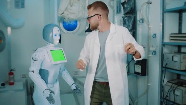 Сумасшедший ученый и гуманоидный робот танцуют в лаборатории — стоковое видео