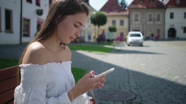 Женщина просматривает интернет по смартфону на площади — стоковое видео