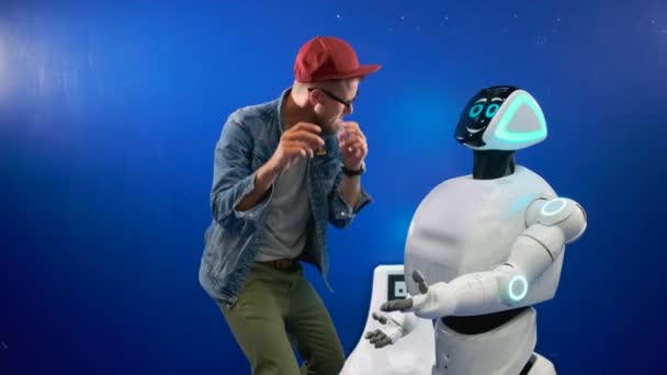 Homem está dançando na frente robô no estúdio, batendo palmas — Vídeo de Stock