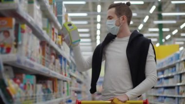 Coronavirüs salgını sırasında süpermarketten alışveriş yapmak, yüzünde maske olan bir adam.