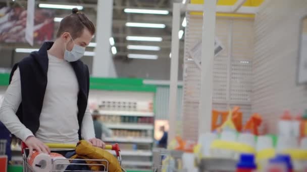 Hombre está almacenando papel higiénico en el supermercado, tiene máscara quirúrgica — Vídeos de Stock