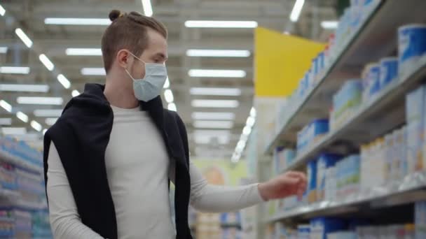 Man met chirurgische masker op het gezicht is winkelen in de supermarkt — Stockvideo