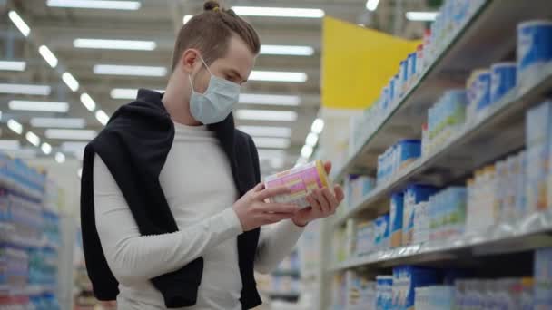 Покупатель в защитной маске выбирает детское питание в супермаркете — стоковое видео