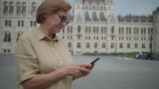 Rijpe vrouw met cel op Kossuth Square in Boedapest, Hongarije — Stockvideo