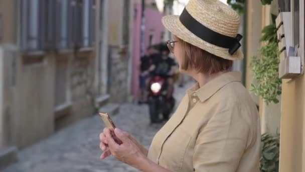 Зріла жінка з мобільним телефоном на вулиці міста — стокове відео
