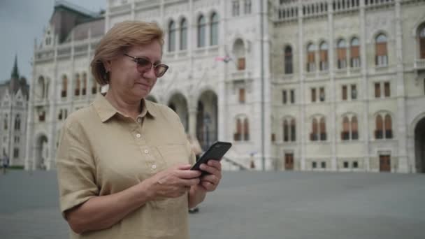 Mulher idosa está digitando sms no telefone na Hungria — Vídeo de Stock
