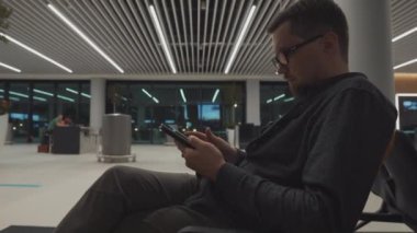 Havaalanında bekleyen adam dijital tablet kullanıyor.