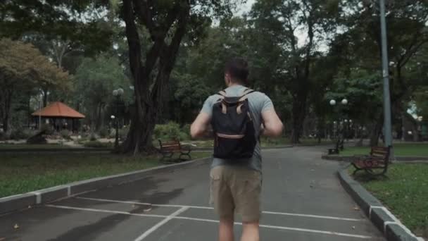 Mann mit Rucksack im grünen Stadtpark — Stockvideo